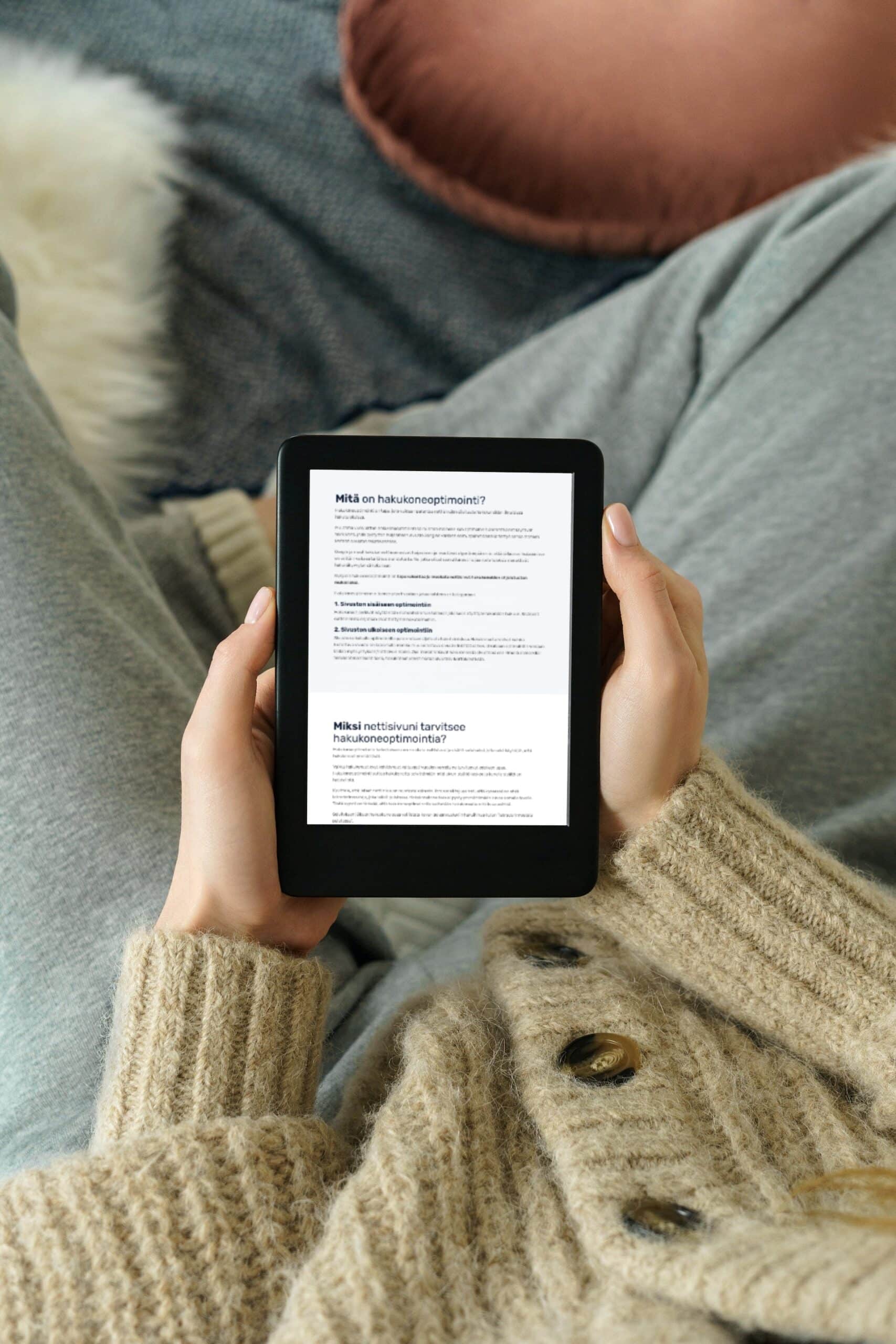 A person reading the SEO guide on an e-reader, with “Mitä on hakukoneoptimointi?” (what is search engine optimization?) on the screen