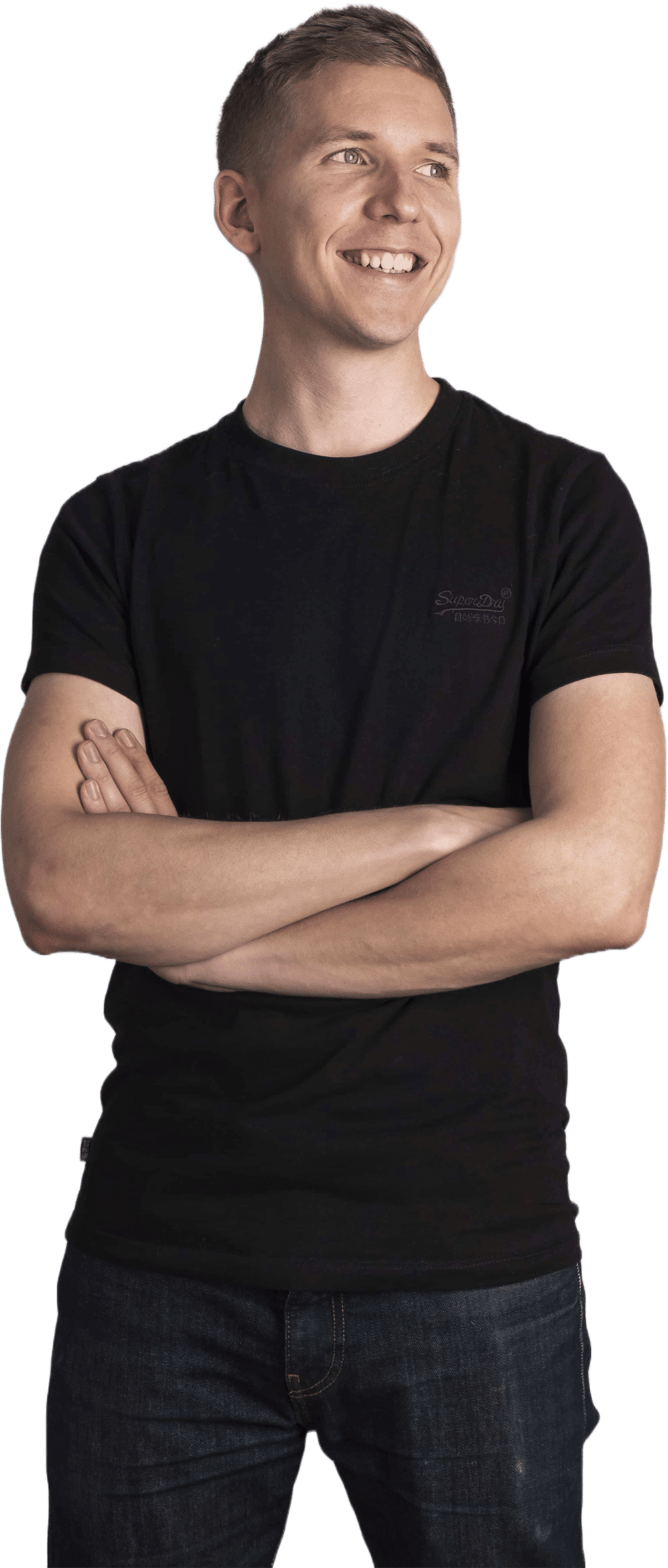 Tapio Kauranen smiling with his arms crossed, in a black T-shirt, looking to the side